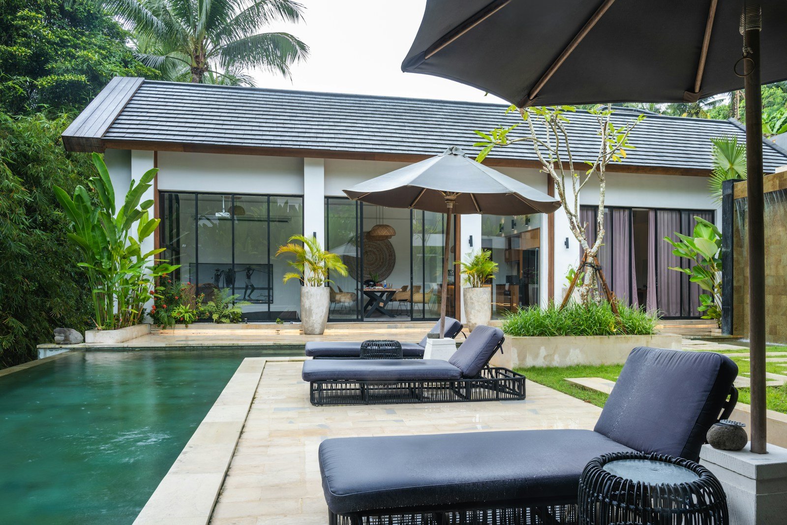 A pool with lounge chairs and an umbrella next to it