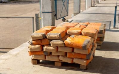 Des palettes de sacs orange empilés sur un sol bétonné à l'extérieur