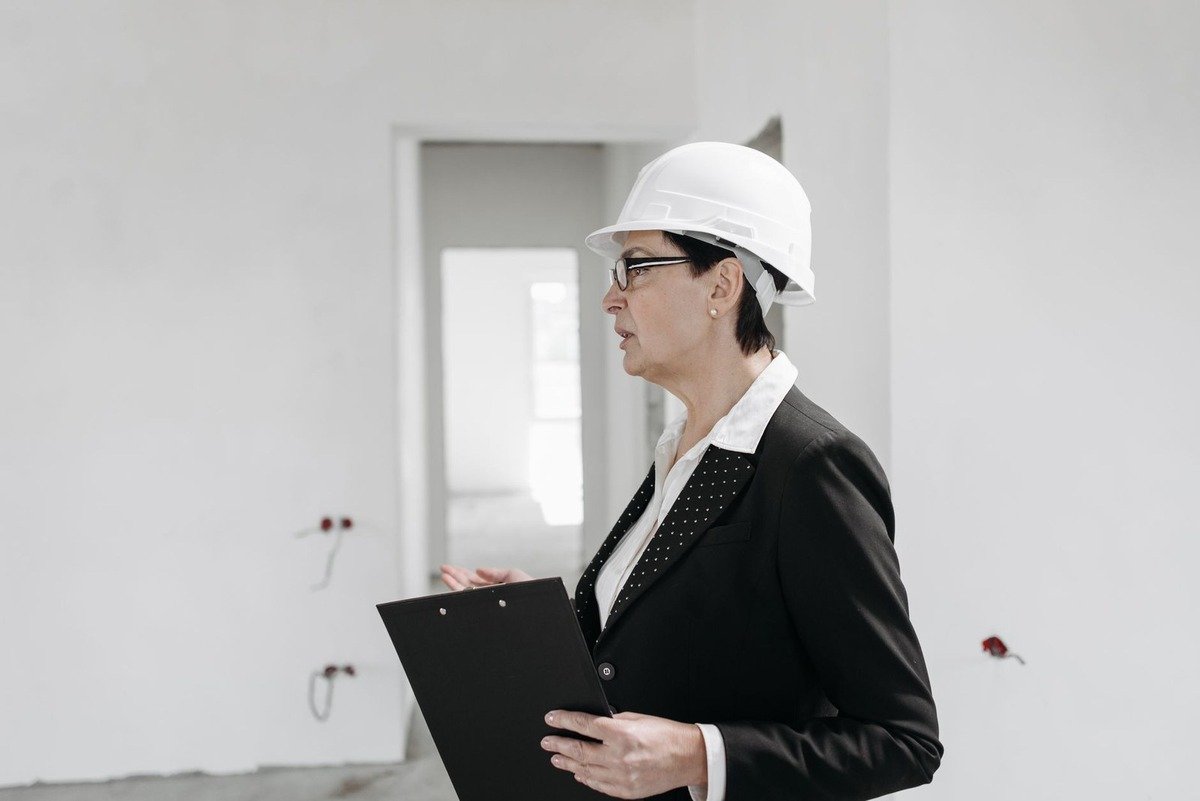 Femme en tenue professionnelle inspecte un bâtiment en construction avec un classeur Femme en tenue professionnelle inspecte un bâtiment en construction avec un classeur