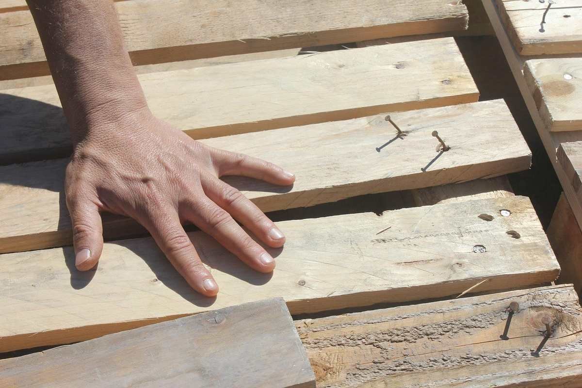 Main posée sur des planches de bois avec des clous saillants Main posée sur des planches de bois avec des clous saillants