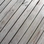 Planches de bois grises posées en diagonale sur un sol extérieur