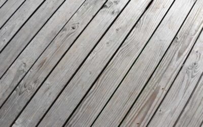 Planches de bois grises posées en diagonale sur un sol extérieur