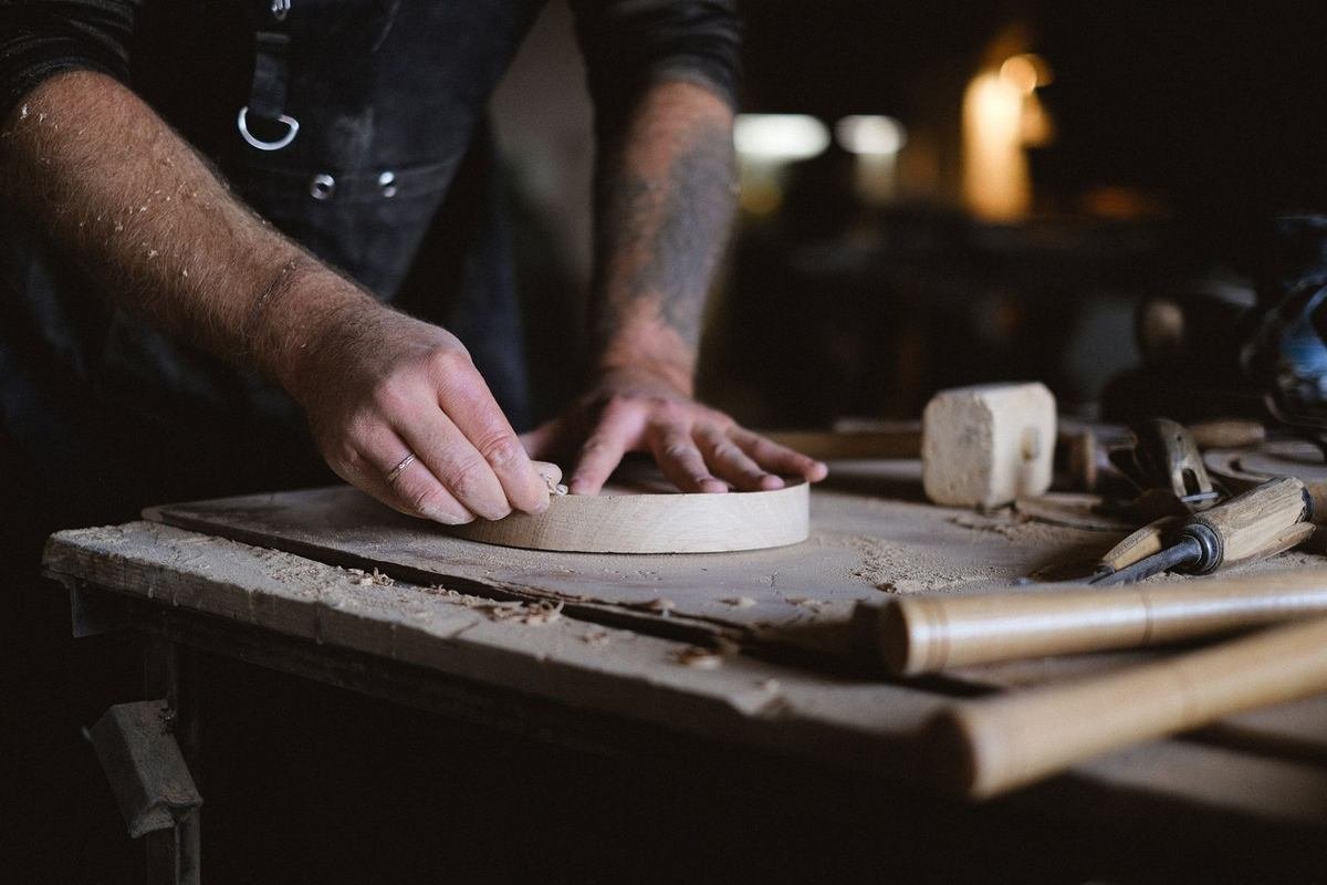 Sculpteur façonnant un disque en bois avec des outils sur une table