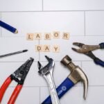 Outils de bricolage sur fond de carreaux blancs avec les mots "LABOR DAY" en lettres de bois