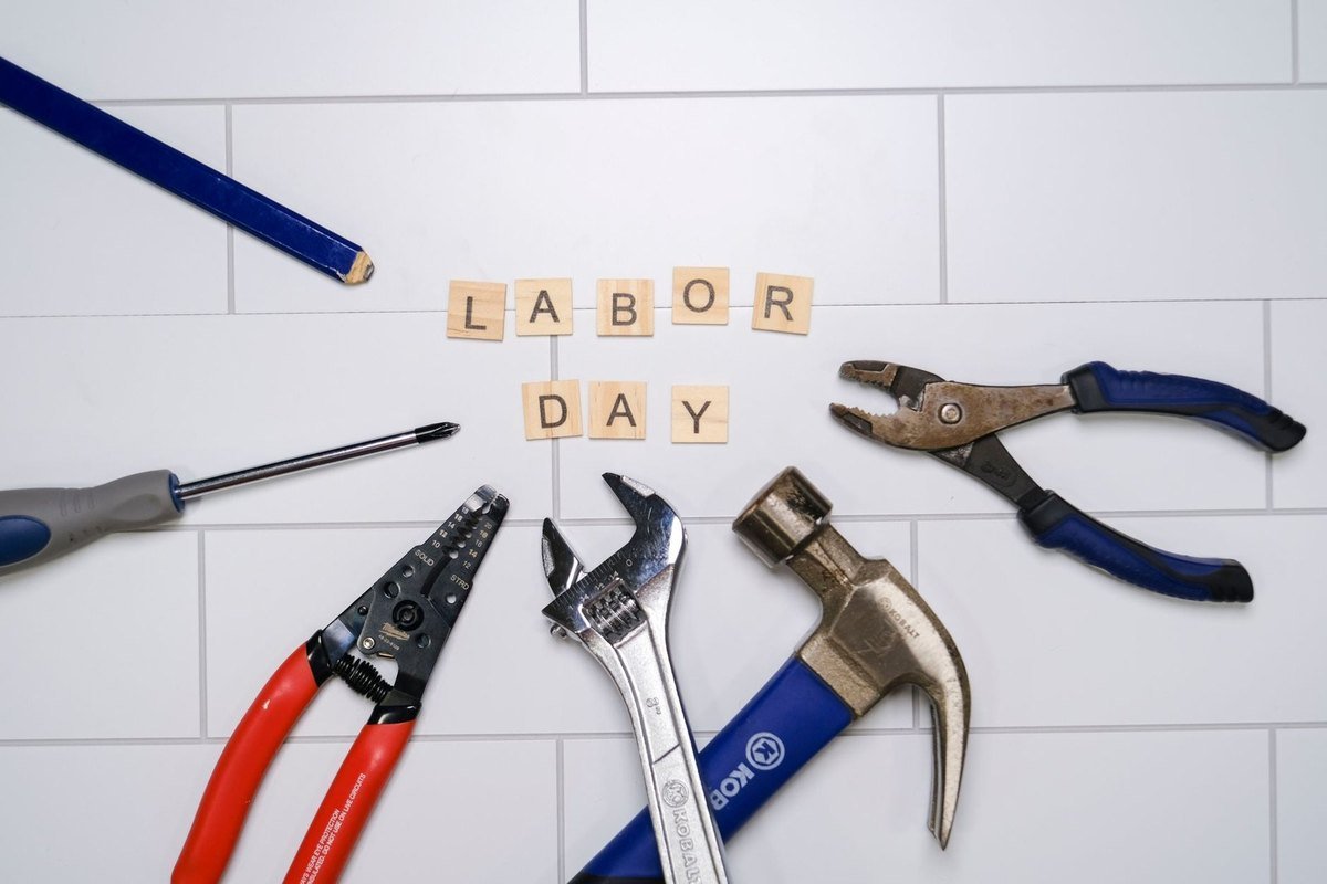 Outils de bricolage sur fond de carreaux blancs avec les mots "LABOR DAY" en lettres de bois