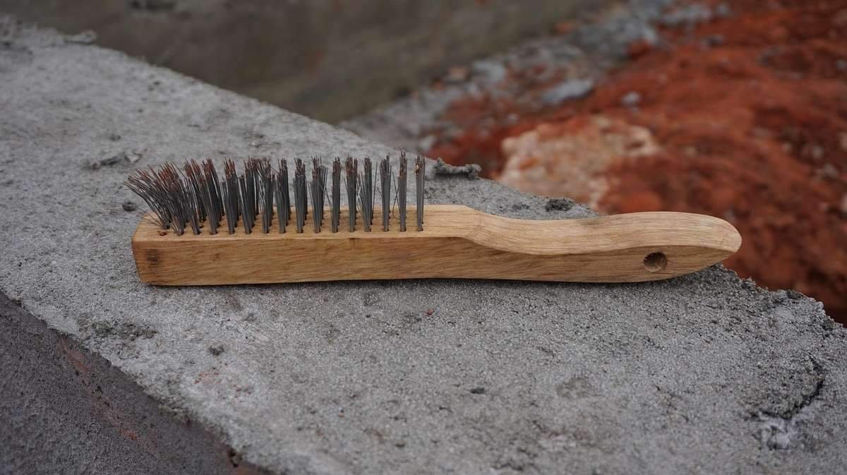 Brosses en bois et métal sur un rebord de béton, arrière-plan terré Brosses en bois et métal sur un rebord de béton, arrière-plan terré