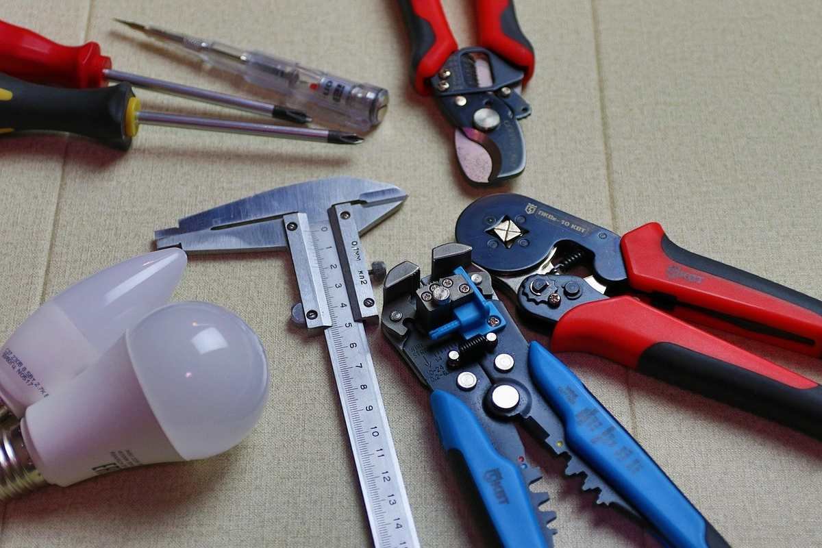 Outils de bricolage sur une table, incluant des pinces, des ciseaux, une règle, et des ampoules non allumées Outils de bricolage sur une table, incluant des pinces, des ciseaux, une règle, et des ampoules non allumées