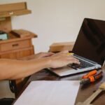 Un homme travaille sur ordinateur portable dans un atelier de menuiserie