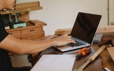 Un homme travaille sur ordinateur portable dans un atelier de menuiserie