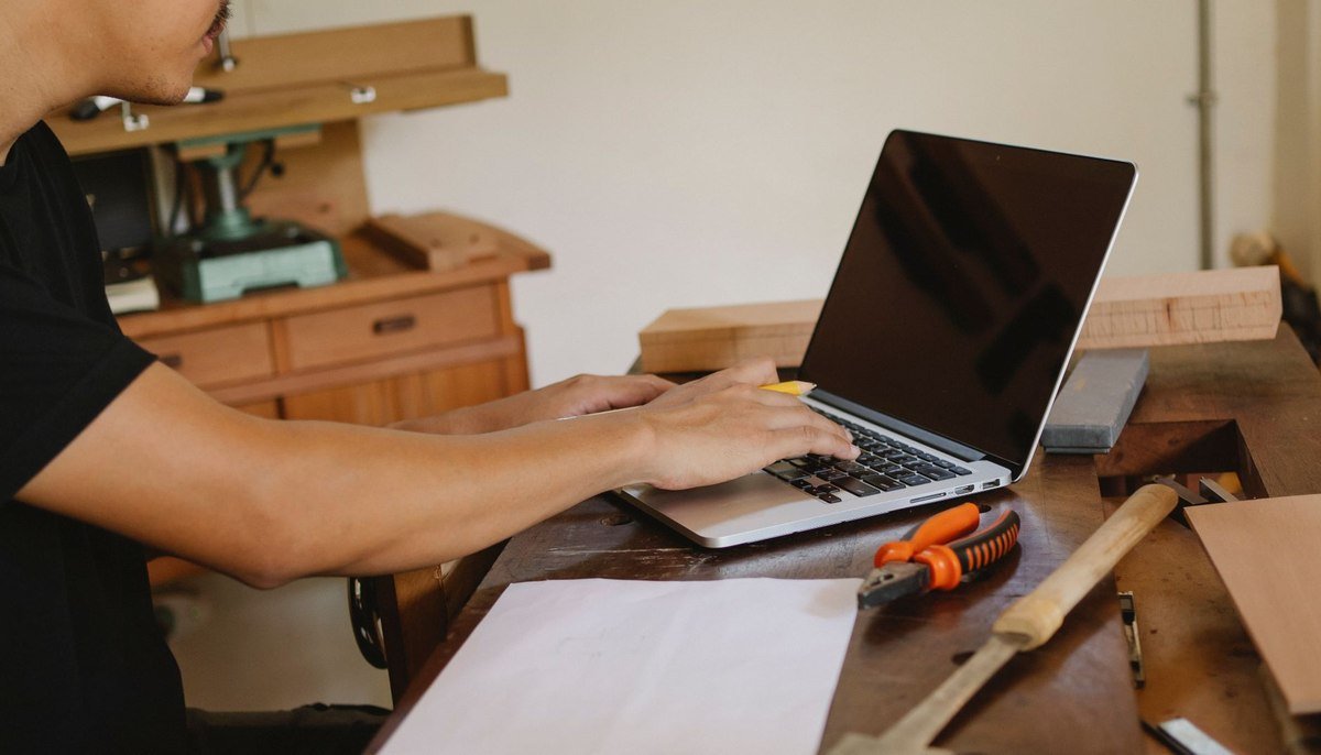 Un homme travaille sur ordinateur portable dans un atelier de menuiserie