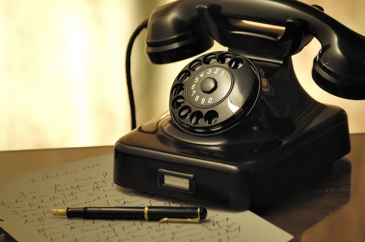 Un téléphone noir ancien un stylo et du papier griffonné sur un bureau Un téléphone noir ancien un stylo et du papier griffonné sur un bureau