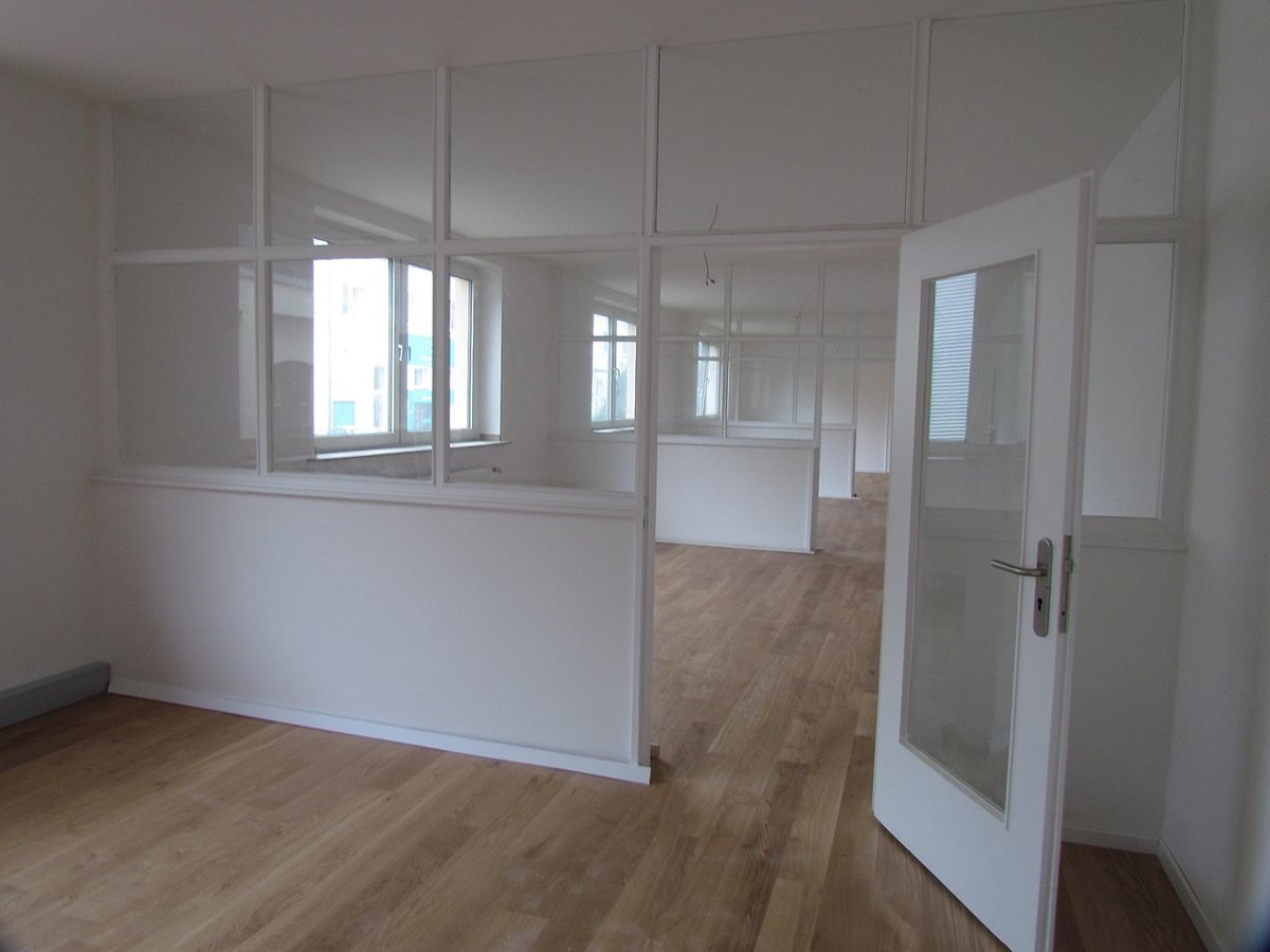 Salle vide avec parquet cloisons vitrées porte ouverte fenêtres