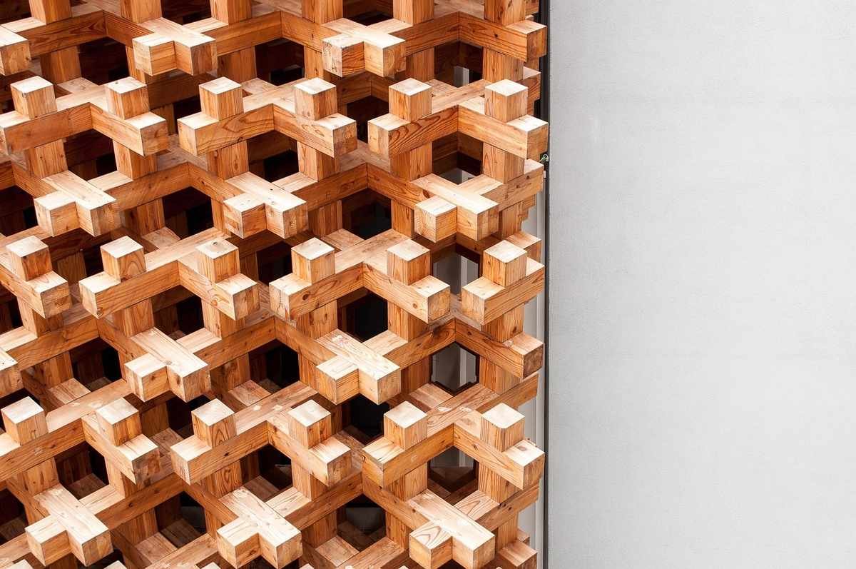 Structure en bois en treillage formant des alvéoles sur un mur blanc