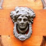 Une tête de métal ornée de feuilles orne une porte en bois