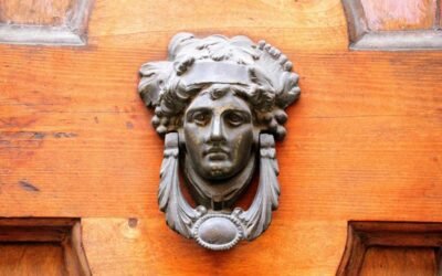 Une tête de métal ornée de feuilles orne une porte en bois
