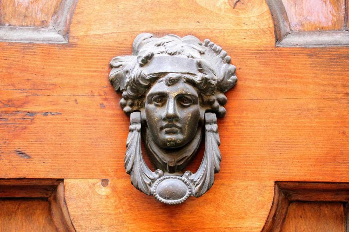 Une tête de métal ornée de feuilles orne une porte en bois