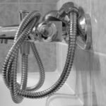 Un robinet de douche avec tuyau flexible accroché au mur