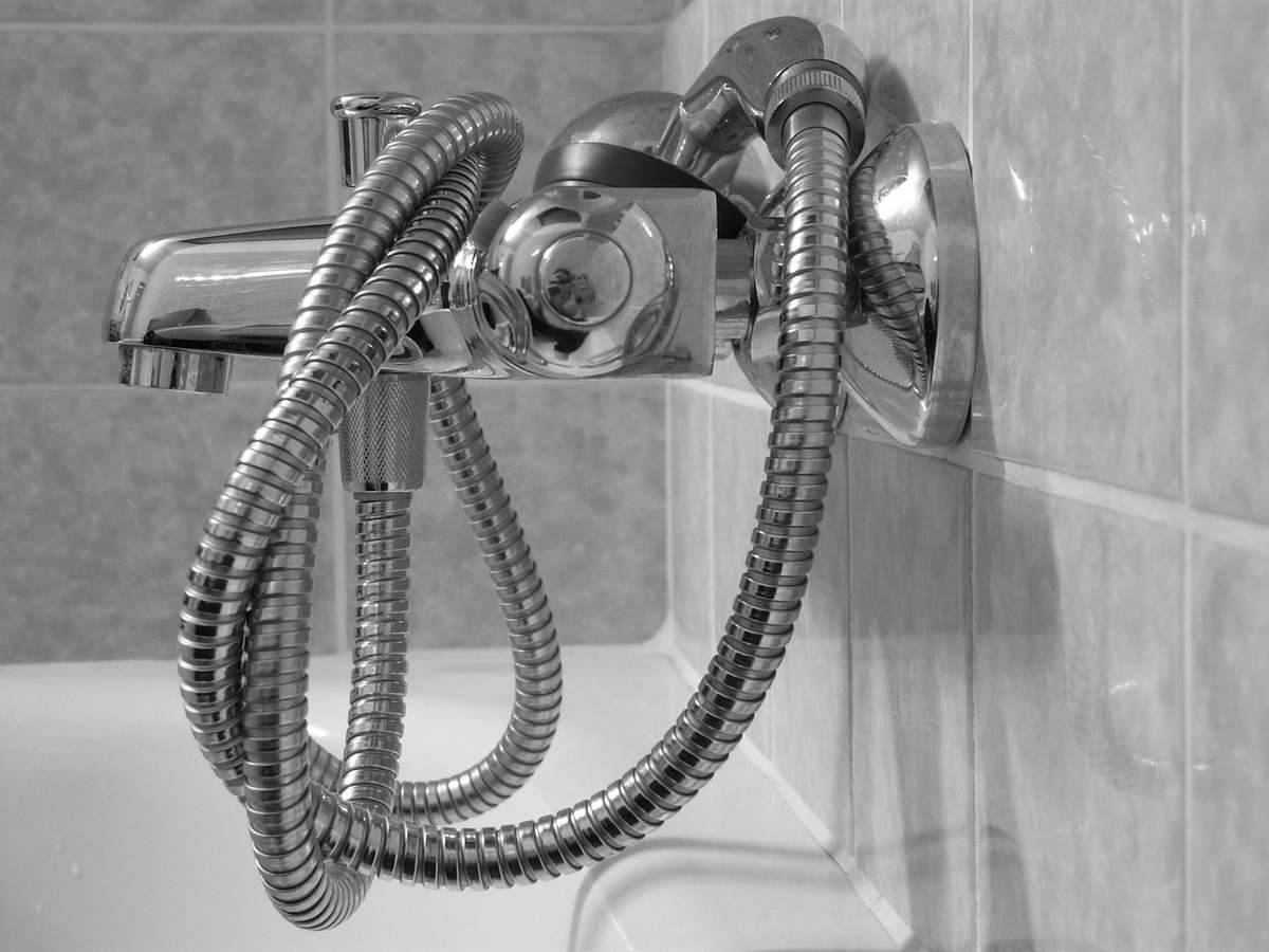 Un robinet de douche avec tuyau flexible accroché au mur
